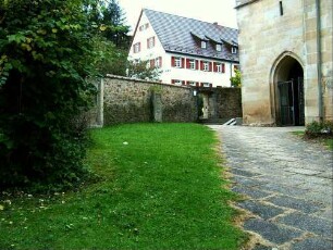 Kirchhof im Westen mit Kirchhofmauer (Wehrgang mit Steinbrüstung im 18 Jh abgetragen) sowie Basis des spätgotischen Kirchturms (1501 angesetzt)