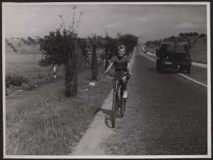 Ein Mädchen fährt auf einer verkehrsreichen Straße, obwohl daneben ein Radweg vorhanden ist