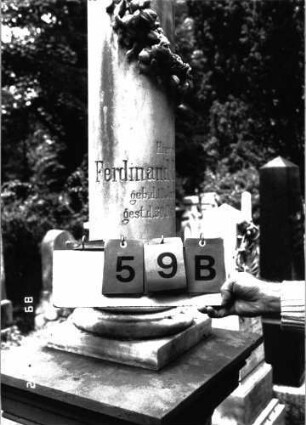 Grabstein 59 (Index: 100101498) Material: Säule weißer Marmor, Postament Sandstein Zustand: deutsche Sockelinschrift verwittert mit Textverlust Maße HxBxT: 200x56x48 cm Beschreibung: postamentierte abgebrochene Säule, Schriftplatte mit ausgezogenen Ecken Symbolik: Blütenkranz um Säule: Grabstein 59B
