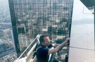 Frankfurt. Deutsche Bank. Fassadenreiniger bei der Arbeit. Auf der Fassade des zweiten Turmes spiegelt sich die Stadt wider