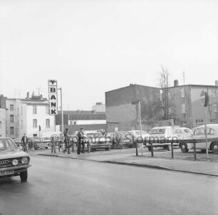 Hagenstraße: Parkplatz mit Pkws: links mehrere Fußgänger und Firmenschild der Volksbank Bad Oldesloe: hinten Rückfronten der Wohn- und Geschäftshäuser Hindenburgstraße / Mühlenstraße: vorn links Front eines Pkws