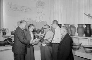 Mehrere Personen begutachten an einem Stand mit Steingutwaren auf der Leipziger Herbstmesse 1955 eine Schale