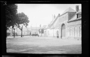 Origny (=Origny-Sainte-Benoite, Dep. Aisne, Frankreich): Platz vor einem Gebäudekomplex mit hohen Eingangstoren