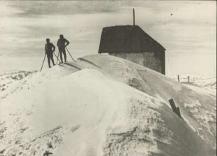Österreich. Tirol. Kitzbüheler Alpen. Winter am Kitzbüheler Horn. Zwei Skifahrer an der Berghütte