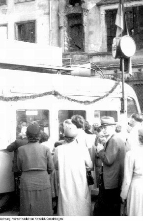 Dresden. 750-Jahr-Feier Dresden, u.a. festliche geschmückte Häuser, Fahnenschmuck auf dem Theaterplatz, Auslage des Café Toscana am Schillerplatz, Platz der Einheit (Albertplatz), Hotelportiers, Andenken, Fahrradtouristen, Richtfest, Modenschau, fahrbahres Postamt, Konzert auf dem Altmarkt, Verkehrsschilder, Juni 1956