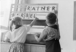 Dresden-Striesen, Fetscherstraße 2. 6. Mittelschule. Ein Schüler und eine Schülerin im Unterricht an einer Lerntafel mit Steckbuchstaben