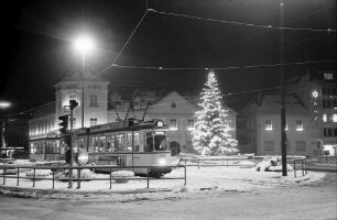 Freiburg: Weihnachtlicher Platz am Siegesdenkmal und Tram und beleuchteter Tannenbaum