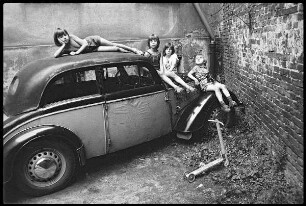 Vier Kinder auf einem alten Auto