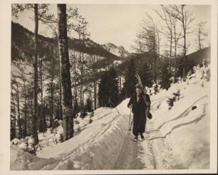 Winter im Hochgebirge. Ein Skifahrer mit geschulterten Ski auf dem Weg zur Skihütte