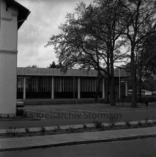 Am Bürgerpark: Parkplatz, Bäume, Jägerzaun: dahinter Stormarnhalle: vorn links Ecke der Jugendfreizeitstätte
