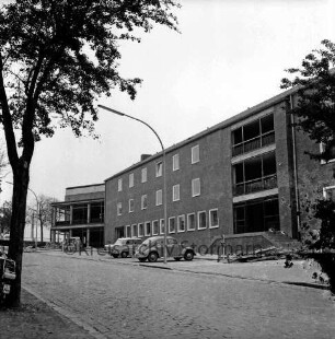 Reimer-Hansen-Straße: Erweiterungsbau [später Gebäude C] vor Fertigstellung: davor Baumaterial und Pkw: hinten links Rohbau des Kreistagssitzungssaales: 15. Oktober 1966
