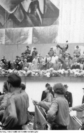 Berlin. 1. Deutschlandtreffen der Jugend. Erich Honecker (Vorsitzender der FDJ) am Mikrophon und Mitglieder der Staatsführung der DDR sowie internationale Gäste im Präsidium während der Friedensdemonstration, Pfingsten, 28. Mai 1950