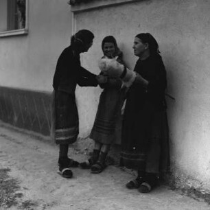 Drei Frauen im Gespräch vor einem Wohnhaus in Razhevo Konare. Die alte Handwerkskunst des Spinnens wird ausgeübt