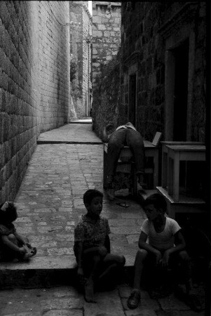 Dubrovnik: Gasse mit zwei Kindern und auf Tisch Schlafendem