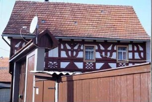 Traufseite eines Fachwerkhauses mit Schmuckelementen; überdachtes Tor
