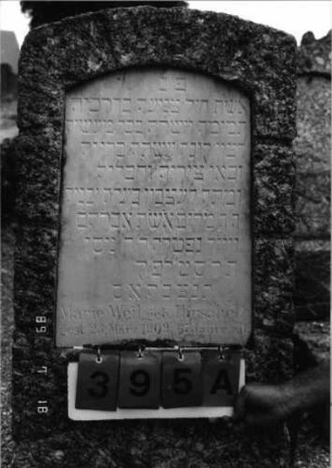 Grabstein 395 (Index: 99797416) Material: Granit, Marmorplatte Zustand: gut Maße HxBxT: 142x51x22 cm Beschreibung: Stele, rustiziert, Segmentbogenabschluß, Sockel: Grabstein 395A