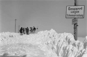 Deutsche Demokratische Republik. Reportage "Was kostet der Schnee?" Winterdiensthelfer beim manuellen Freiräumen einer Landstraße, im Vordergrund Sperrschild wegen Schneeverwehung