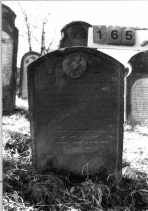 Grabstein 165 (Index: 100116279) Material: Sandstein Zustand: gut Maße HxBxT: 88x58x9 cm Beschreibung: Stele mit Segmentbogenabschluß, eingetieftes Schriftfeld Symbolik: Blüte Besonderheit: Kindergrab: Grabstein 165