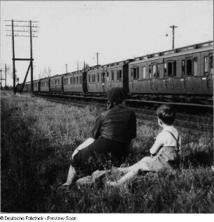 Personenzug mit Abteilwagen auf der freien Strecke unweit Bahnhof Berlin-Lichterfelde Süd, im Vordergrund als Zuschauer an der Böschung sitzend Mutter und Sohn