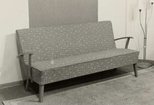 Sofa : Sofa (1956; Polstermöbelkombinat Rabenau-Oelsa) in Ausstellungskoje vor Tapetenstreifen und mit Stehlampe