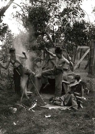 Kinder beim Indianerspiel in einem Garten (Tanz um das Feuer vor dem Tipi)