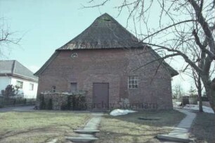 Hauptstraße 33: Bauernhaus mit Reetdach: Giebelseite Wirtschaftstrakt, mit Tür in zugmauertem Scheunentor