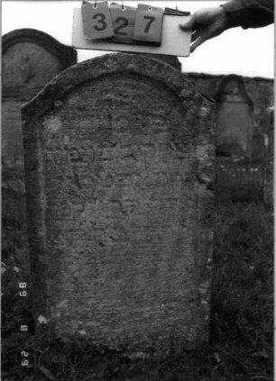 Grabstein 327 (Index: 100107754) Material: Kalkstein Zustand: stark verwittert Maße HxBxT: 138x62x20 cm Beschreibung: Stele, geschwungen eingezogener Rundbogenabschluß, Schriftfeld eingetieft: Grabstein 327