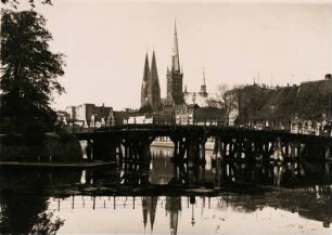 Lübeck. Blick vom Malerwinkel über die Trave zur Dankwartsbrücke, einer hölzernen Fußgängerbrücke. Im Hintergrund die Doppeltürme der Marien- und der Turm der Petrikirche