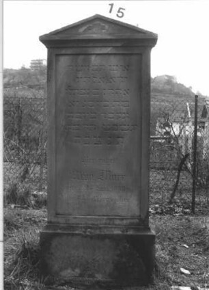 Grabstein 15 (Index: 99804999) Material: Sandstein Zustand: leicht verwittert Maße HxBxT: 141x60x17 cm Beschreibung: Stele auf Sockel mit abgesetztem Dreiecksgiebel: Grabstein 15