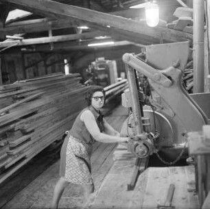 Holz : Grimma. Portrait einer Arbeiterin mit Schürze an einer Holzsägemaschine