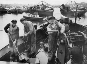 Kähne auf der Oberelbe. Schiffer beim Klar Schiff machen. Sie schrubben das Deck. Ein Schiffer steht an der Winsch