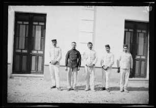 Nador (Marokko): 5 Soldaten ("die Ordonnanzen") in hellgestreiften Uniformen (Rayadillos), einer in dunkler Uniformjackie und dreien mit niedriger, flacher Feldmütze vor einem hellen Gebäude (Gruppenbild)