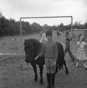 Dorffest: Kinder mit einem Pony, dahinter der Fußballplatz