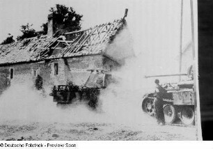 Reproduktion einer Fotografie von einer Gebäuderuine sowie gepanzerten Wehrmachtsfahrzeugen