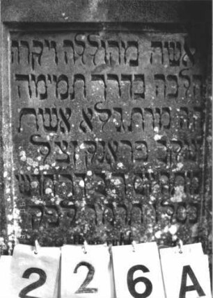 Grabstein 226 (Index: 100107001) Material: Sandstein Zustand: verwittert, Mittelaufsatz fehlt Maße HxBxT: 129x63x20 cm Beschreibung: Ädikulaartige Stele mit Rundbogenabschluß, Mittelaufsatz fehlt, Halbsäulen, Schriftfeld rechteckig eingetieft, Sockel Symbolik: floral: Grabstein 226A