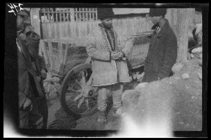 Odobești (=Rumänien): "Rumäne in Tracht" im Gespräch mit seinem Sohn (?) neben einem Pferdewagen (Nahaufnahme)