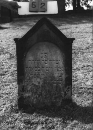 Grabstein 52 (Index: 100113759) Material: Sandstein Zustand: leicht verwittert Maße HxBxT: 90x55x11 cm Beschreibung: Stele mit eingezogenem Spitzgiebel, vertiefter Textteil in Form einer Stele mit Rundbogen: Grabstein 52