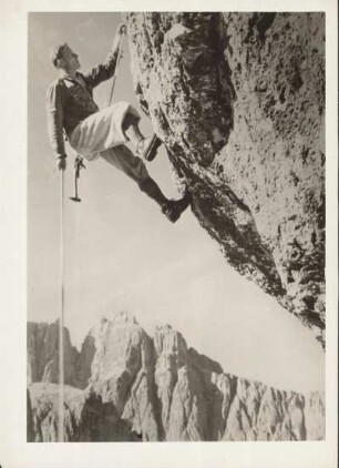 Hochgebirge. Ein Bergsteiger an einem Überhang am Fels. Er ist mit einem Seil gesichert