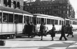 Berlin. Straßenbahn (Triebwagen mit zwei Hängern) der Linie 77 in einem Haltestellenbereich. Fahrgäste beim Einsteigen