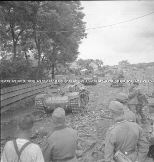Deutsche Soldaten und Panzer auf staubigen Landstraße