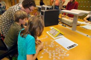Kinder bei der "Bibliotheksrallye für Kinder" (Kinder lernen die Bibliothek spielerisch auf einer Rallye kennen. Die Maya-Zahlen weisen den Weg) im Serviceraum der Deutschen Fotothek
