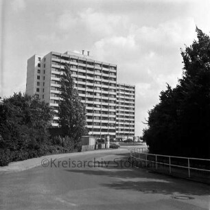 Königsberger Straße: mittig parkender Pkw, dahinter die Wohnhochhäuser der Straße Im Hölk (Siedlung Ehmkenberg II), Blick Richtung Südosten