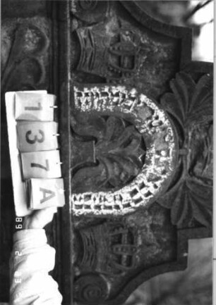 Grabstein 137 (Index: 99751946) Material: Sandstein Zustand: verwittert mit großem Textverlust Maße HxBxT: 164x98x14 cm Beschreibung: ädikulaart. St. m. Viertelsäulen, in Voluten auslaufender Rundbogenaufsatz Symbolik: drei Kronen, Eichenlaub, Ranken: Grabstein 137A