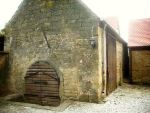 Kirchhof im Nordnordwesten mit Gaden (im Baubestand 15-16 Jh) über Giebelseite mit Kellereingang (Wehrgang der Kirchhofmauer im 19 Jh abgetragen und Pult- durch Satteldach ersetzt)