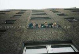 Vier männliche Jugendliche schauen aus dem Fenster nach unten