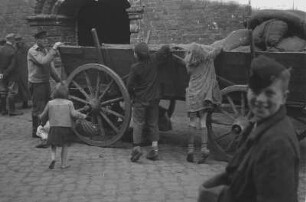Stralsund? Leiterwagen eines Fuhrwerkes mit Kartoffeln. Bauer beim Entladen und zwei Kinder beim Klauen vom Wagen