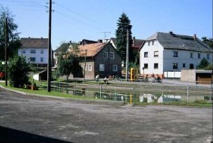 Dorfplatz mit Dorfteich, hinten Jugendliche mit Moped bei der Telefonzelle; Häuser