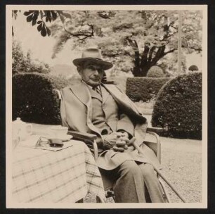 Der alte Rudolf Kassner im Garten mit Hut und Mantel im Rollstuhl