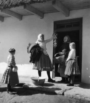 Reisefotos. Ungarn. Frauen und Mädchen mit aufgefädelten Pepperoni- oder Paprikaschoten vor dem Eingang eines Wohnhauses (wahrscheinlich in Csömör)