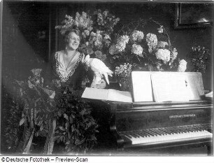 Elisabeth Rethberg mit Blumenarrangement und Geschenken : Porträt Elisabeth Rethberg aus feierlichem Anlaß mit Blumenarrangement und Geschenken in ihrer Wohnung. Fotografie von Ursula Richter, um 1928